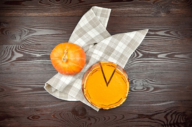 pumpkin pie on cutting board on brown wooden table