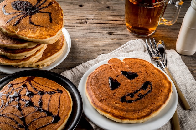 Pumpkin pie pancakes decorated with chocolate syrup in a traditional style - spider web, spider, jack lantern