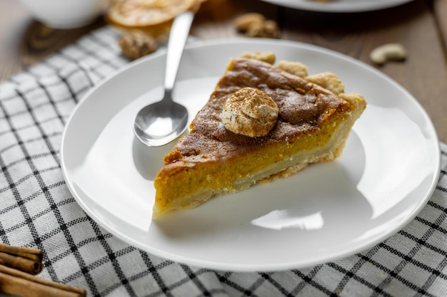 Pumpkin Pie a Thanksgiving pie made with whipped cream on a white plate wooden table background