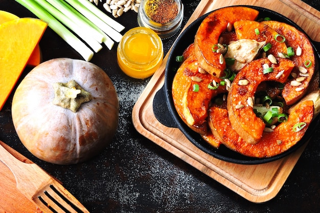 Pumpkin pieces baked in a small frying pan with greens and seeds. Baked pumpkin. Vegan lunch with spicy baked pumpkin. Useful autumn snack. Halloween lunch.