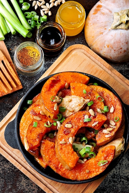 Pumpkin pieces baked in a small frying pan with greens and seeds. Baked pumpkin. Vegan lunch with spicy baked pumpkin. Useful autumn snack. Halloween lunch.