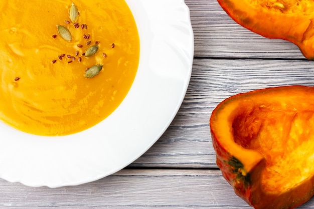 Pumpkin porridge in a white plate on a light wooden background creamy soup for vegetarians