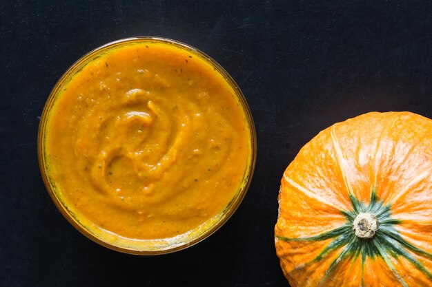 Pumpkin puree in glass bowl on the black background