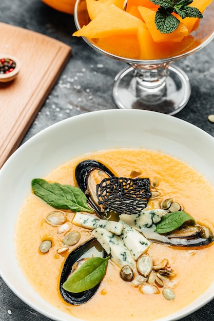 Pumpkin puree soup with pumpkin seeds seafood mussels shrimps blue cheese mold served in bowl vertical image top view place for text