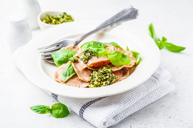 Pumpkin ravioli with pesto sauce in a white plate. 