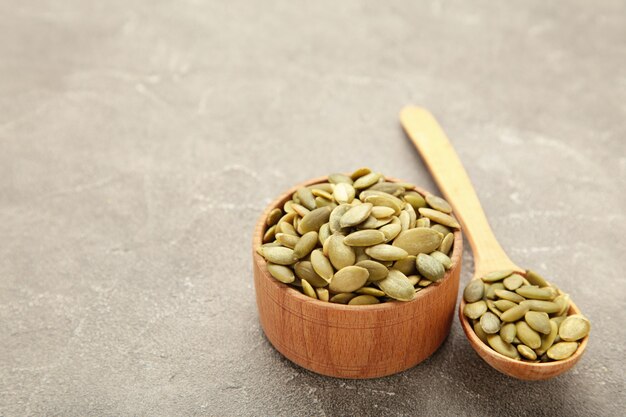 Pumpkin seed in bamboo bowl and spoon on grey