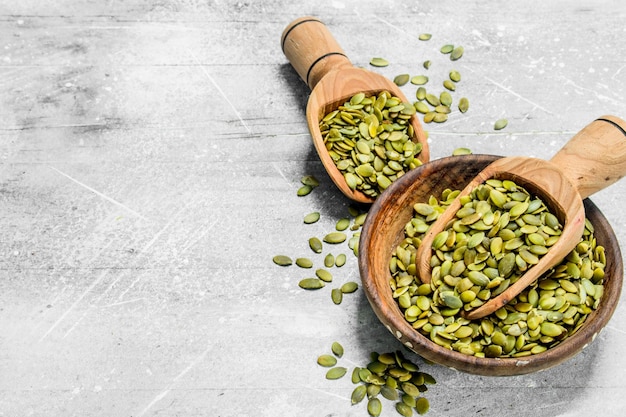 Pumpkin seeds in bowl with wooden scoop