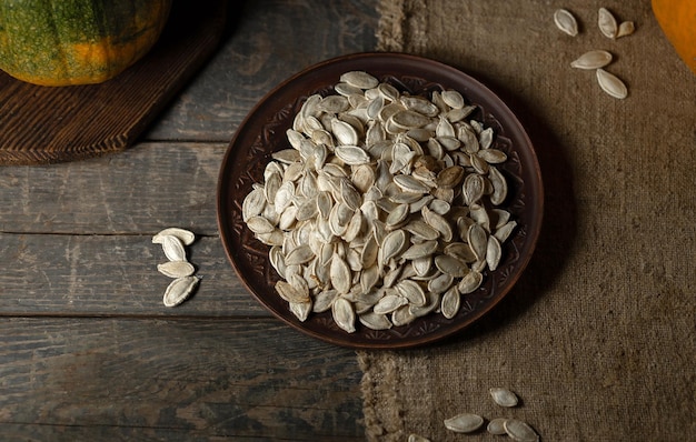 Pumpkin seeds on a brown plate on a wooden background