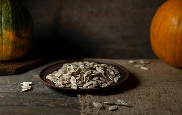 Pumpkin seeds on a brown plate on a wooden background