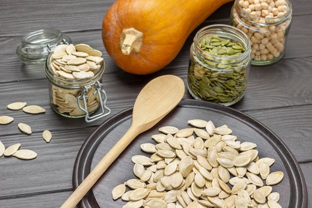 Pumpkin seeds in glass jars Wooden spoon and seeds on board