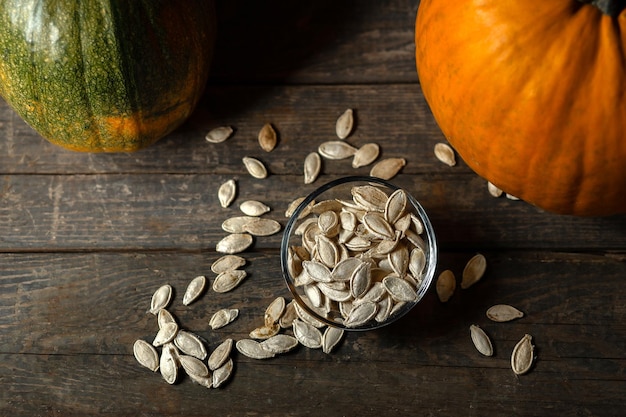 Pumpkin seeds in a glass saucer on a wooden background