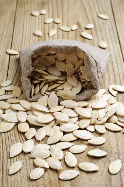 Pumpkin seeds in a sack on the wooden table