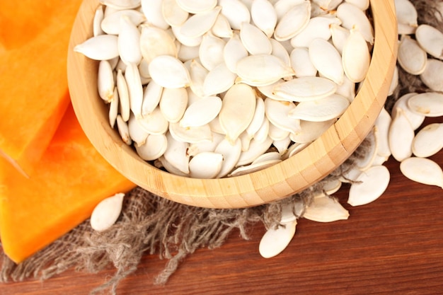 Pumpkin seeds in wooden bowl on wooden background