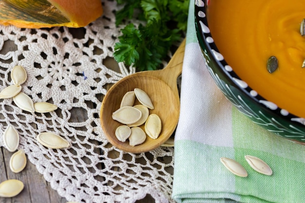 Pumpkin seeds in a wooden spoon and a bowl of soup