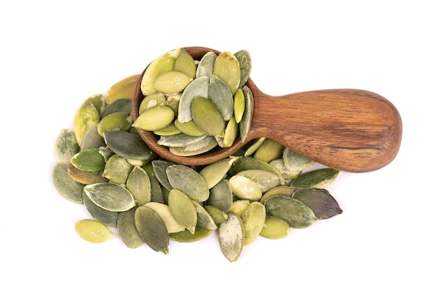 Pumpkin seeds in wooden spoon, isolated on white background.