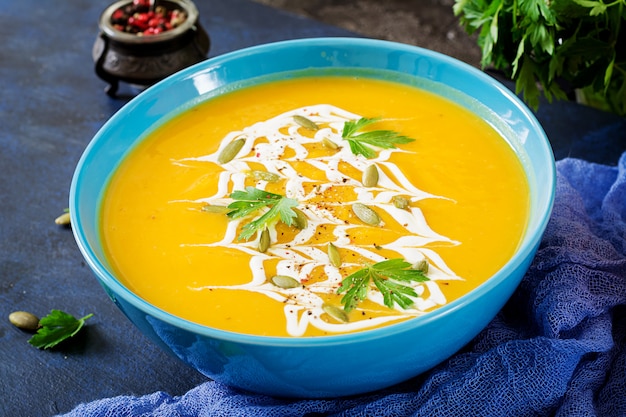 Pumpkin soup in a bowl served with parsley  and pumpkin seeds. Vegan soup.  Thanksgiving day food.