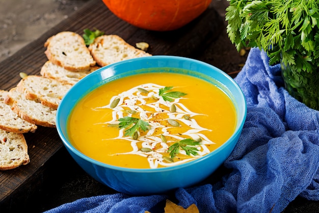 Pumpkin soup in a bowl served with parsley  and pumpkin seeds. Vegan soup.  Thanksgiving day food.