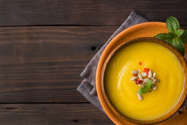 Pumpkin soup mashed with spices in wooden bowls on dark boards.