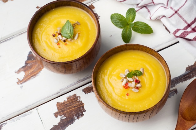 Pumpkin soup mashed with spices in wooden bowls on light boards.