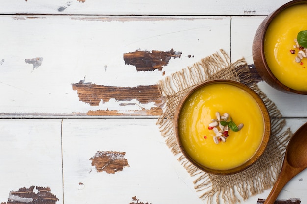 Pumpkin soup mashed with spices in wooden bowls on light boards.