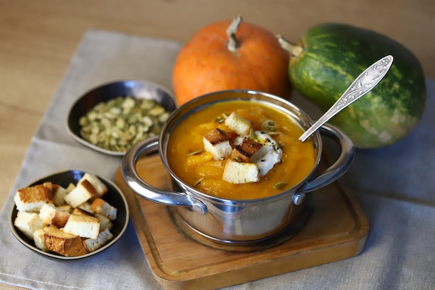 Pumpkin soup in a saucepan with croutons