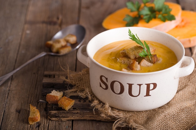 Pumpkin soup. Vegetarian soup with pumpkin seeds in bowl on wooden table, top view