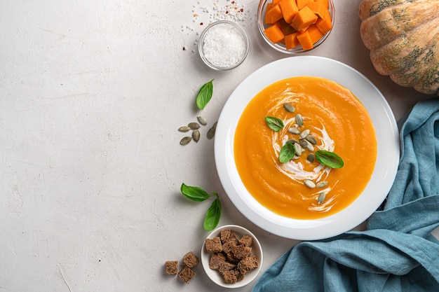 Pumpkin soup with carrots and cream on a gray background with space for copying