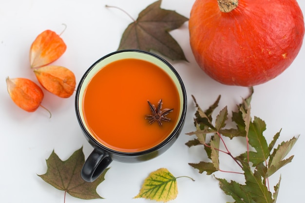 Pumpkin soup with cream and pumpkin seeds and a bucket on a white wooden background Copy space