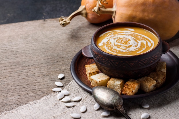 Pumpkin soup with cream and sesame seeds with croutons on wooden surface