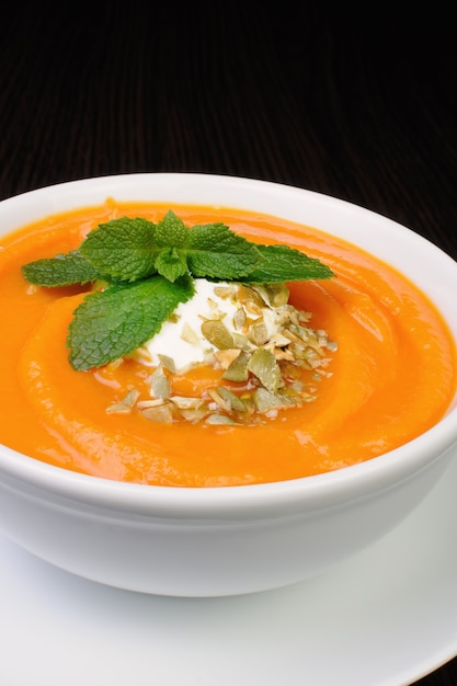 Pumpkin soup with sour cream sauce flavored  pumpkin seeds  and mint