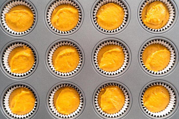 Pumpkin spice cupcake batter in a cupcake pan with liners.