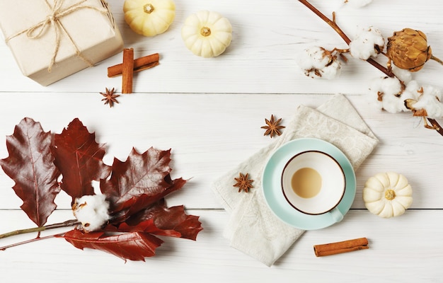 Pumpkin spice latte empty cup. Coffee cup, cinnamon sticks, red oak leaves and small yellow pumpkins. Autumn fall hot drinks