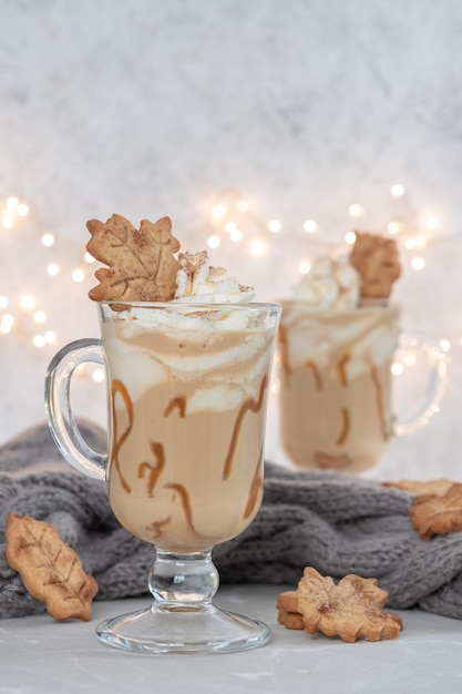 Pumpkin spice latte in a glass mug with caramel and cinnamon with autumn decoration