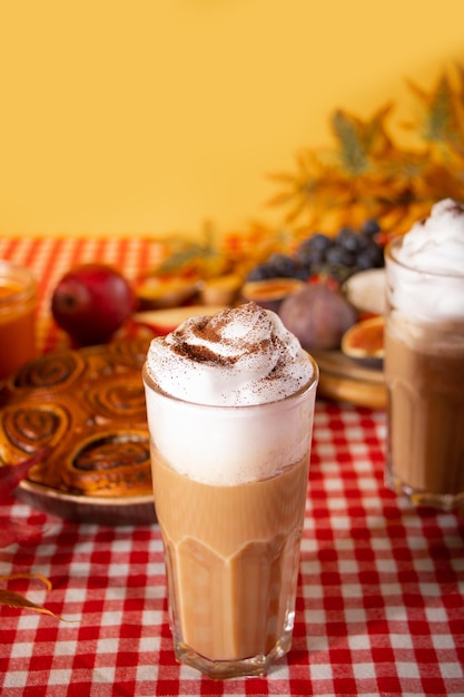 Pumpkin spice whipped latte in glass Hot autumn drink beverage Nearby delicious pie and appetizers fruits and cheese