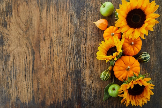 Pumpkin and sunflowers over old wooden background with copy space autumn background decoration