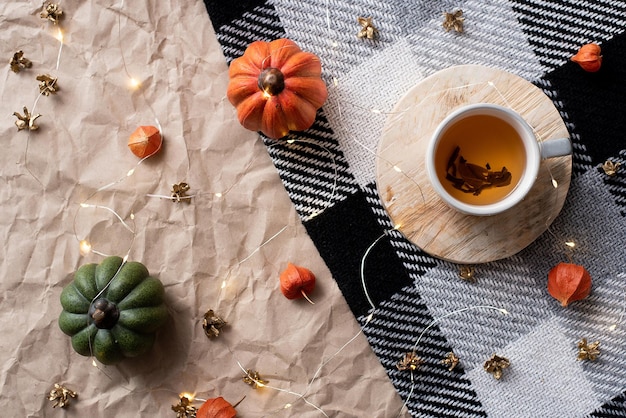 Pumpkin with a cup of tea on a checkered plaid autumn october decor flat lay