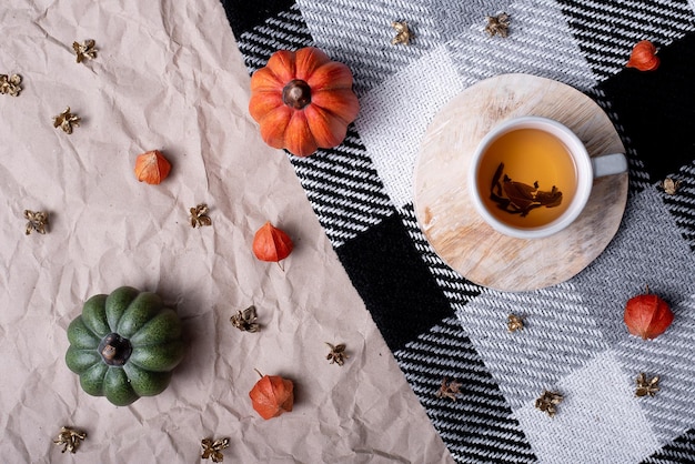 Pumpkin with a cup of tea on a checkered plaid autumn october decor flat lay