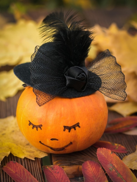 Pumpkin with a face on the table with autumn leaves