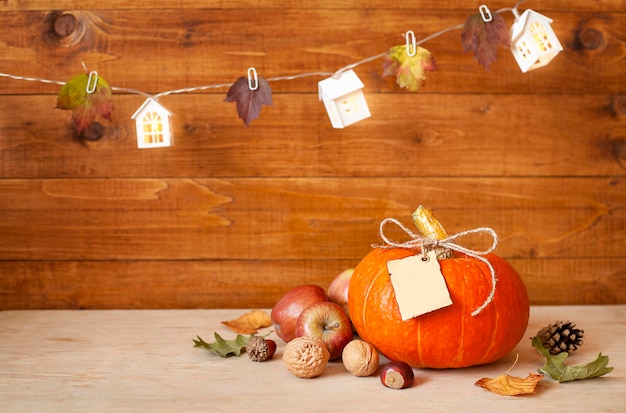 pumpkin with paper tag, apples and nuts lie on a wooden background