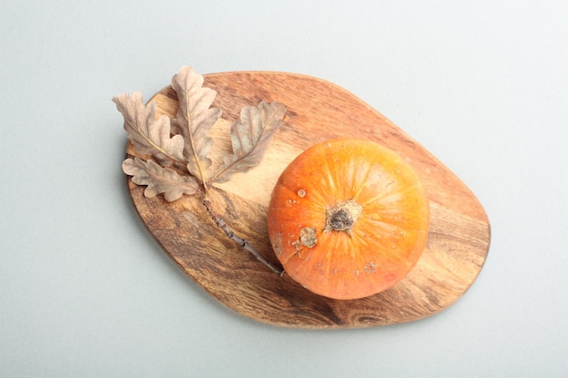 Pumpkin on a wooden cutting board on a gray background