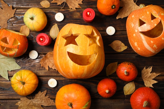 Pumpkins, leaves and candies on wooden table, top view