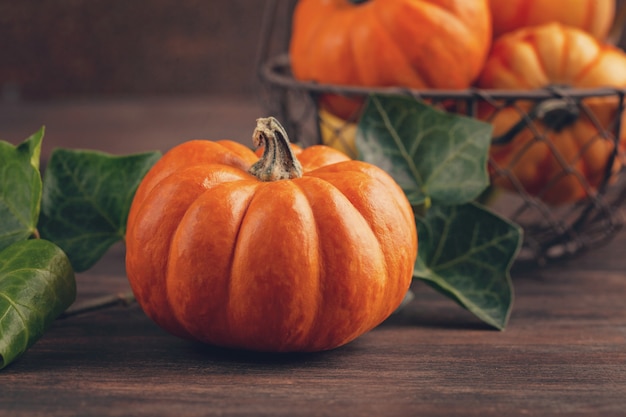 Pumpkins and leaves over wooden background with copy space