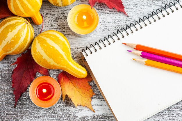 pumpkins and notebook beside lit candle