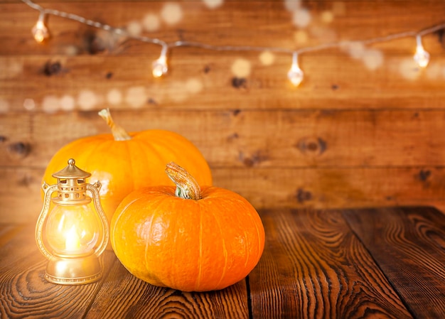 pumpkins with lanterns and garlands on a wooden background close-up