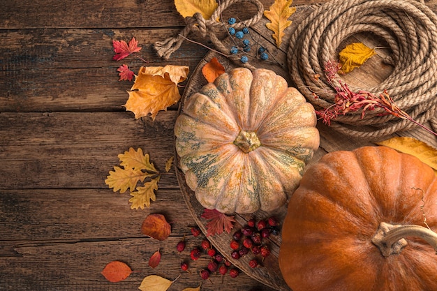 Pumpkins and yellow leaves on a wooden brown background