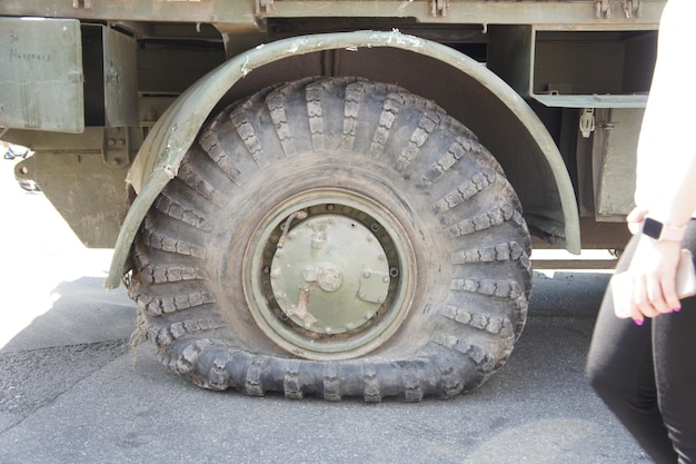 A punctured and flat tire of military equipment of the armored personnel carrier Military conflict the shelling of the wheel Punctured tire of a military offroad vehicle