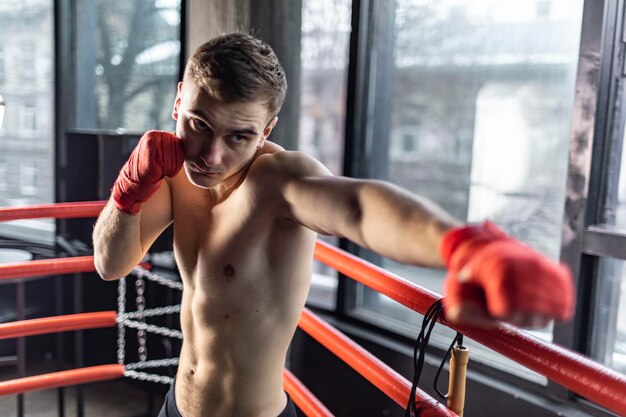 Photo punhing man with red bandages in the ring before wide window