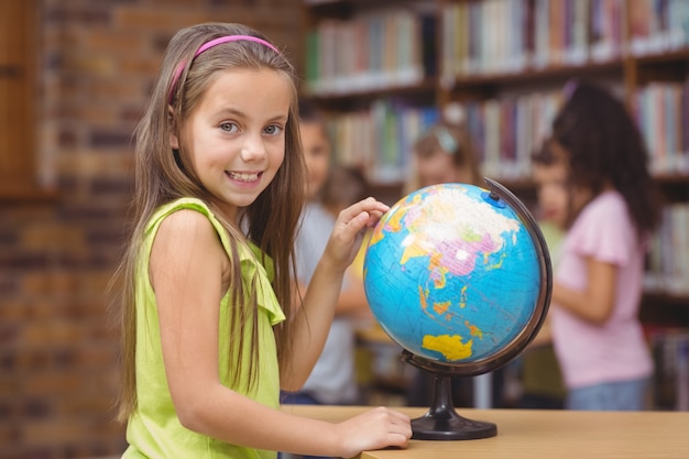 Pupil in library pointing to globe