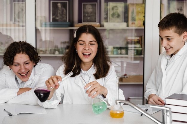 Pupils holding flasks with liquid for experiments in laboratory Education concept Group of pupils studying chemistry lesson in school