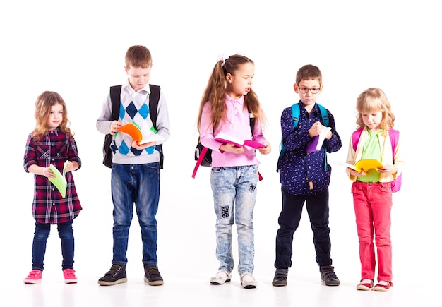 Pupils with backpacks holding books in the hands are ready to go to school. Back to school concept